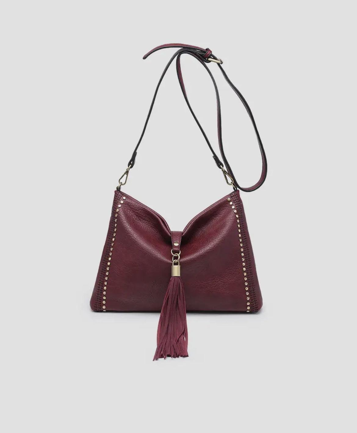 Wine red studded tassel crossbody bag with adjustable strap.