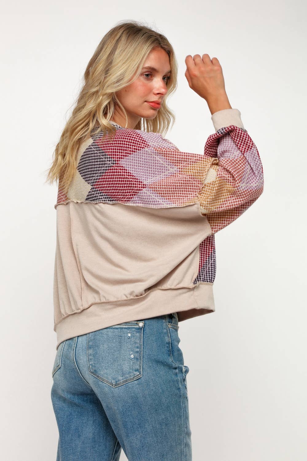 Side view of women’s oversized knit sweater with colorful argyle design in mustard, lilac, burgundy, and black.